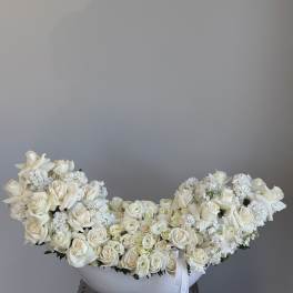 Large white rose arrangement in a white bowl vase