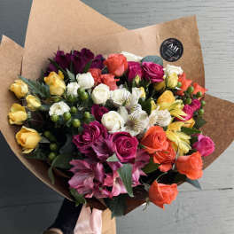 Mixed bouquet of colorful roses and alstroemeria wrapped in brown paper