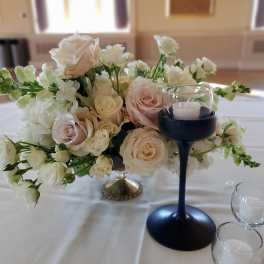 White and blush roses arranged with white blooms in a low centerpiece.