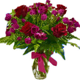 Red roses and pink spray roses in a glass vase with a ribbon