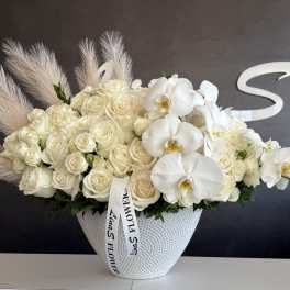 Cream roses and white orchids arranged in a textured white vase.