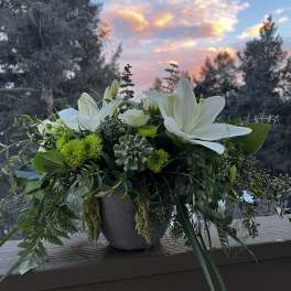 White lilies and green blooms in a gray vase