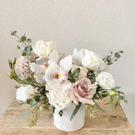 White and blush roses with orchids in a white vase