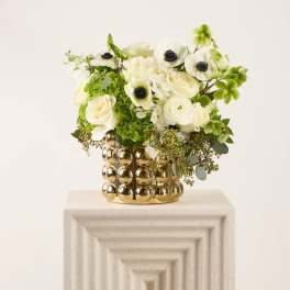 White and green floral arrangement in a gold textured vase