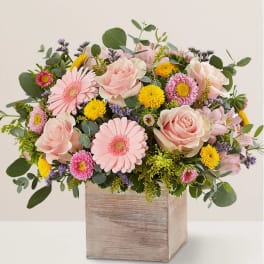 Pink roses and daisies arranged in a wooden box