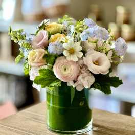Pastel mixed flower arrangement in a green glass vase