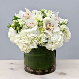 White hydrangeas and orchids in a green glass vase