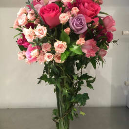 Tall bouquet of pink and lavender roses in a clear glass vase