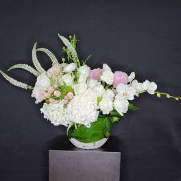 White and pink floral arrangement in a round vase with long arching stems