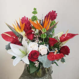 Tropical bouquet with red roses, white lilies, and bird-of-paradise in a glass vase