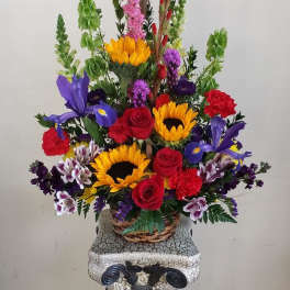 Colorful mixed flower arrangement in a wicker basket on a pedestal