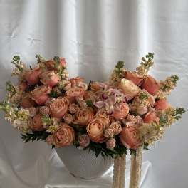 Large peach and cream floral arrangement in a white textured vase