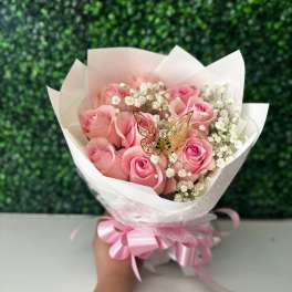 Pink rose bouquet wrapped in white paper with a ribbon
