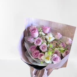 Bouquet of pink roses and white flowers wrapped in pale paper