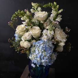 White roses and blue hydrangeas in a dark blue vase