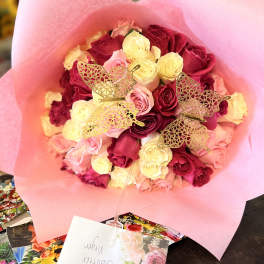 Bouquet of pink, red, and cream roses wrapped in pink paper
