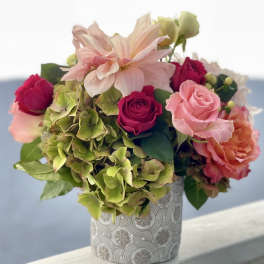 Pink and peach roses with green hydrangeas in a patterned vase
