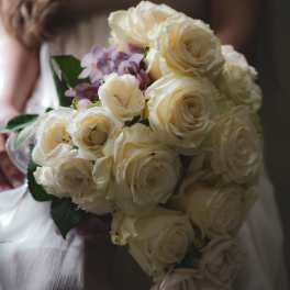 Bride holding a bouquet of cream roses and pale purple flowers