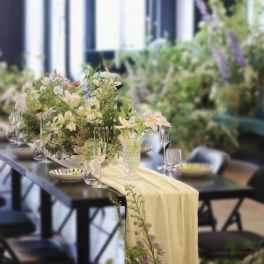 Pastel floral centerpiece on a table with a pale draped runner
