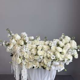 White roses and calla lilies arranged in a white vase