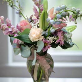 Pastel bouquet of mixed flowers in a glass vase with a ribbon