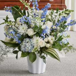 White and blue floral arrangement in a white vase