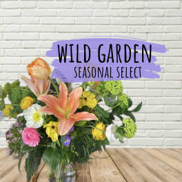 Mixed bouquet with lilies, poppies, and roses in a glass vase
