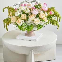 Pastel floral arrangement in a pedestal vase with arching greenery