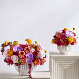 Two colorful flower arrangements in white vases on pedestal stands