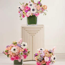 Three pastel floral arrangements in square glass vases