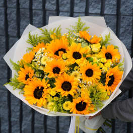 Bouquet of orange sunflowers and yellow flowers wrapped in white paper