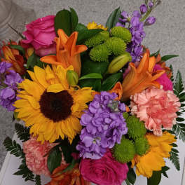 Colorful mixed bouquet with sunflowers, roses, lilies, and purple blooms