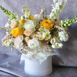 Bouquet of yellow, white, and blush flowers in a white hat box