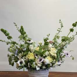 Low floral arrangement in a textured white pot with pale roses and white blooms
