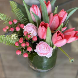 Pink tulips and pale pink ranunculus in a glass vase