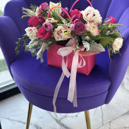 Pink and white flower arrangement in a gift bag with ribbon