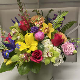 Bright mixed bouquet in a round hatbox with roses, orchids, lilies, and hydrangea
