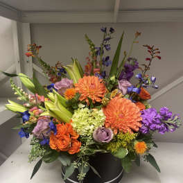 Colorful mixed flower arrangement in a black round box