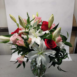 Bouquet of red and pink roses with white lilies in a glass vase