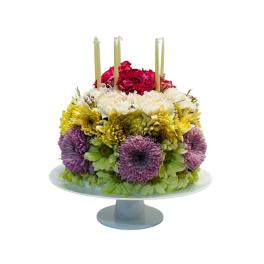 Round floral cake with candles on a pedestal stand