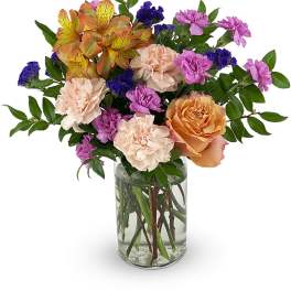 Mixed bouquet of roses, carnations, and alstroemeria in a clear glass vase