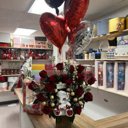 Red rose arrangement with a teddy bear and heart balloons