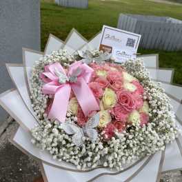 Pink and cream rose bouquet with baby’s breath and a pink ribbon