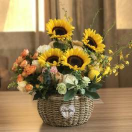 Sunflower and rose arrangement in a woven basket