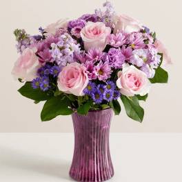Pink and purple mixed bouquet in a tall purple vase