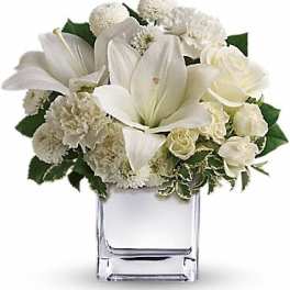 White floral arrangement in a clear square vase