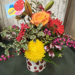 Mixed flower arrangement in a strawberry-patterned mug with a thank-you card