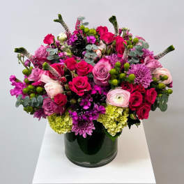 Mixed pink and purple flower arrangement in a dark glass vase