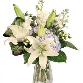 White lilies and pale hydrangeas in a clear glass vase