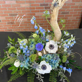 Blue and white floral arrangement with driftwood and shells